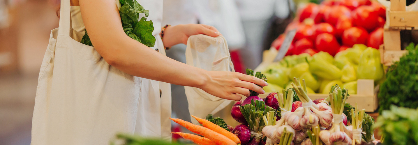 Female hands puts fruits and vegetables in cotton produce bag at