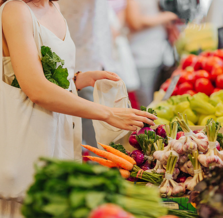 Female hands puts fruits and vegetables in cotton produce bag at